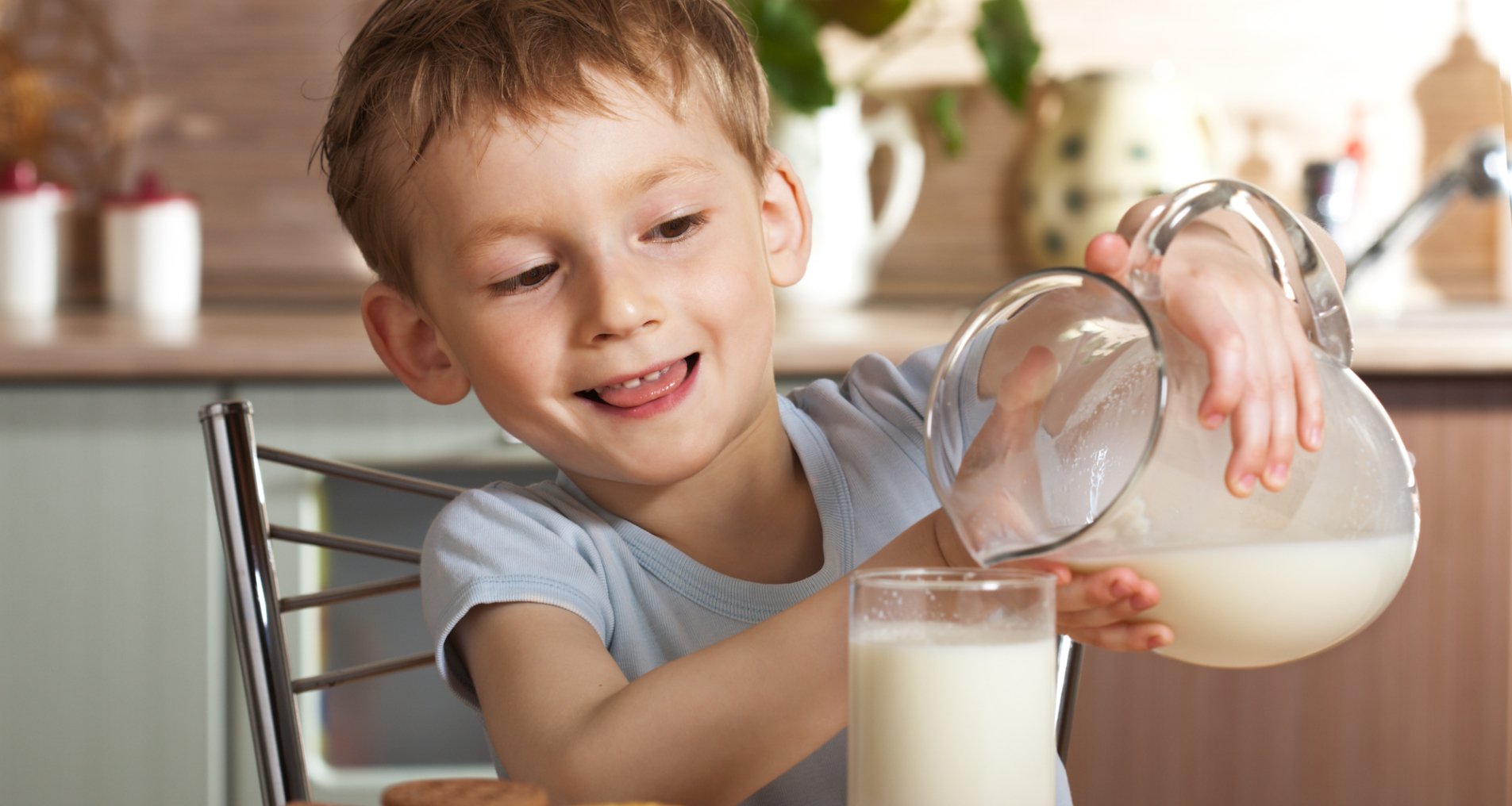 Ребенок наливает молоко в стакан.