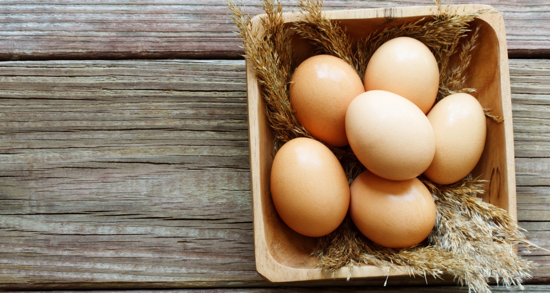 Шесть куриных яиц в деревянной миске