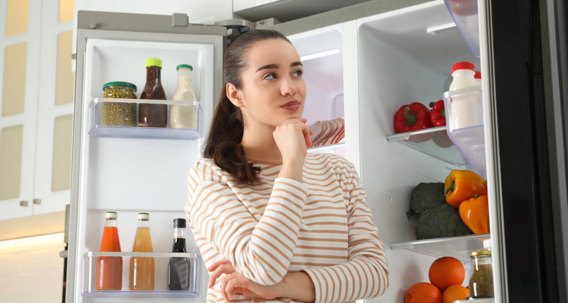 Женщина возле холодильника с продуктами.