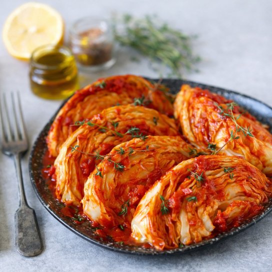 Запеченная капуста в тарелке на фоне деревянного стола.